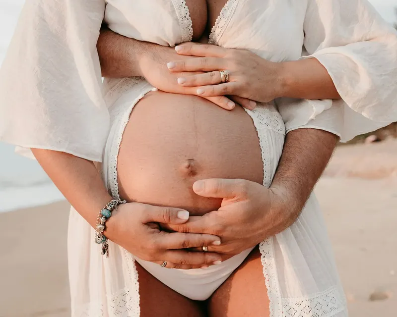 Zwei Hände liegen schützend auf einem Babybauch